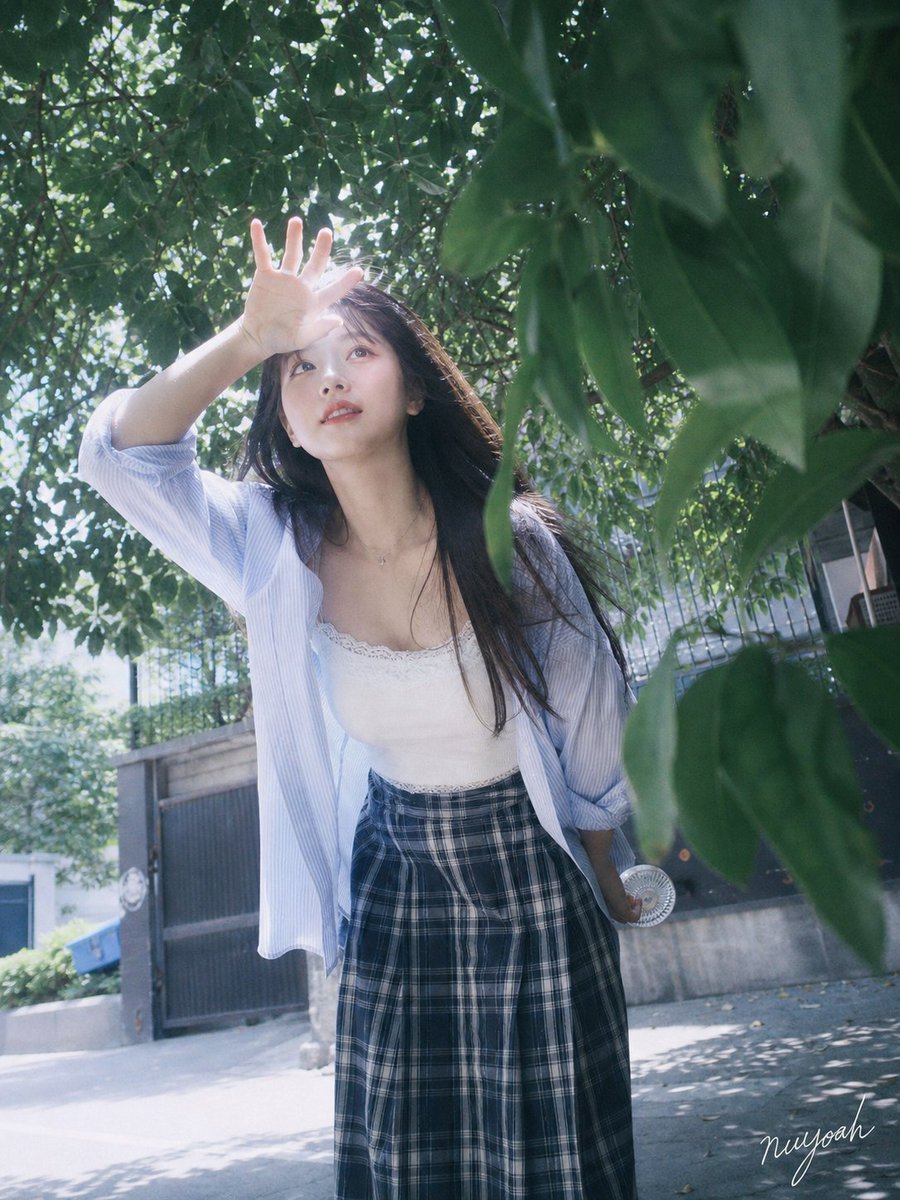 成年年轻女性，清透桃粉甜美妆，深棕长直发与自然风吹碎发，白色蕾丝吊带搭配宽松浅蓝条纹衬衫、深蓝格纹下装；盛夏城市街...