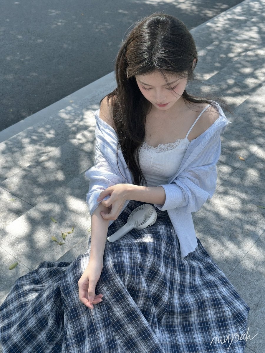 成年年轻女性，清透桃粉甜美妆，深棕长直发与自然风吹碎发，白色蕾丝吊带搭配宽松浅蓝条纹衬衫、深蓝格纹下装；盛夏城市街... - alternate