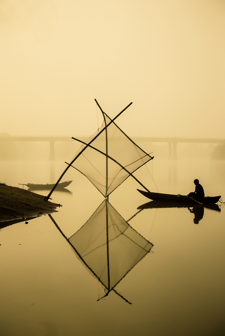 A tranquil river landscape engulfed in a thick, monochrom...