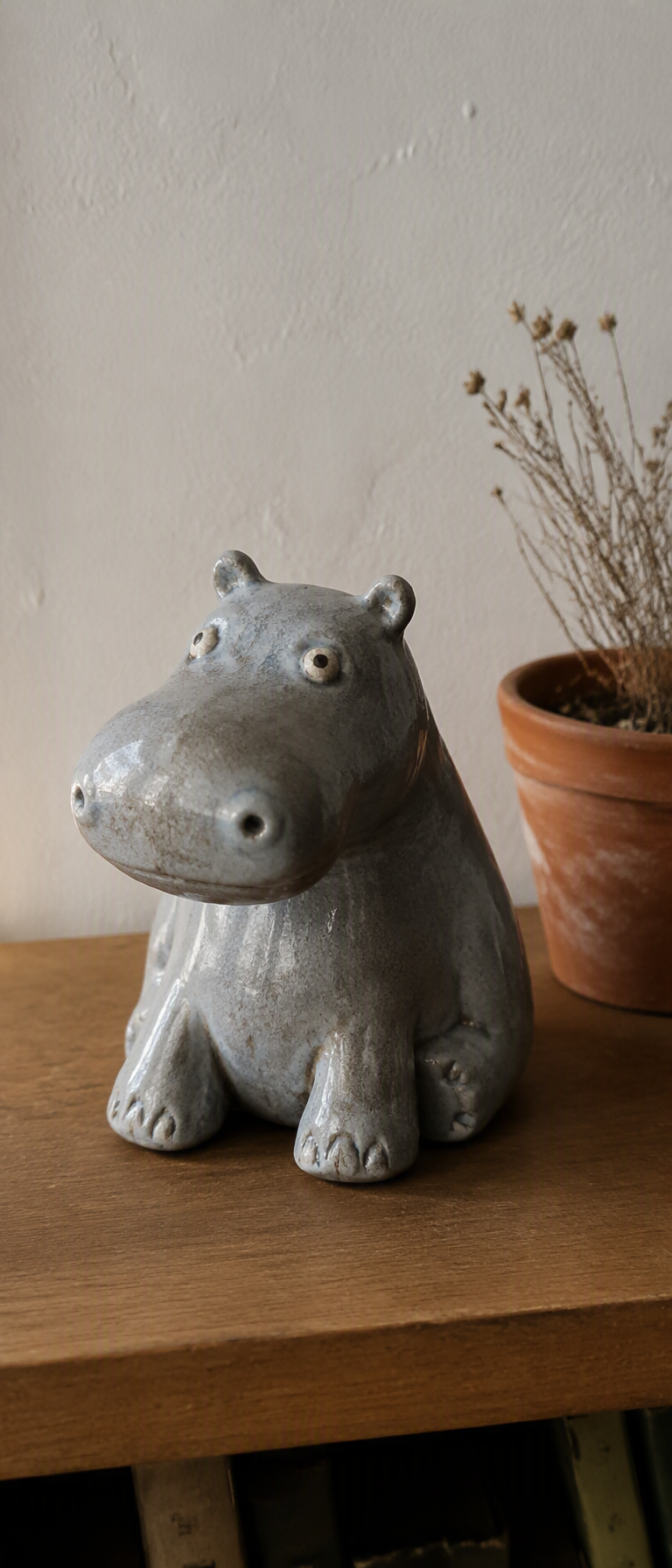 A vertical 9:20 photograph of a handmade ceramic hippopot...