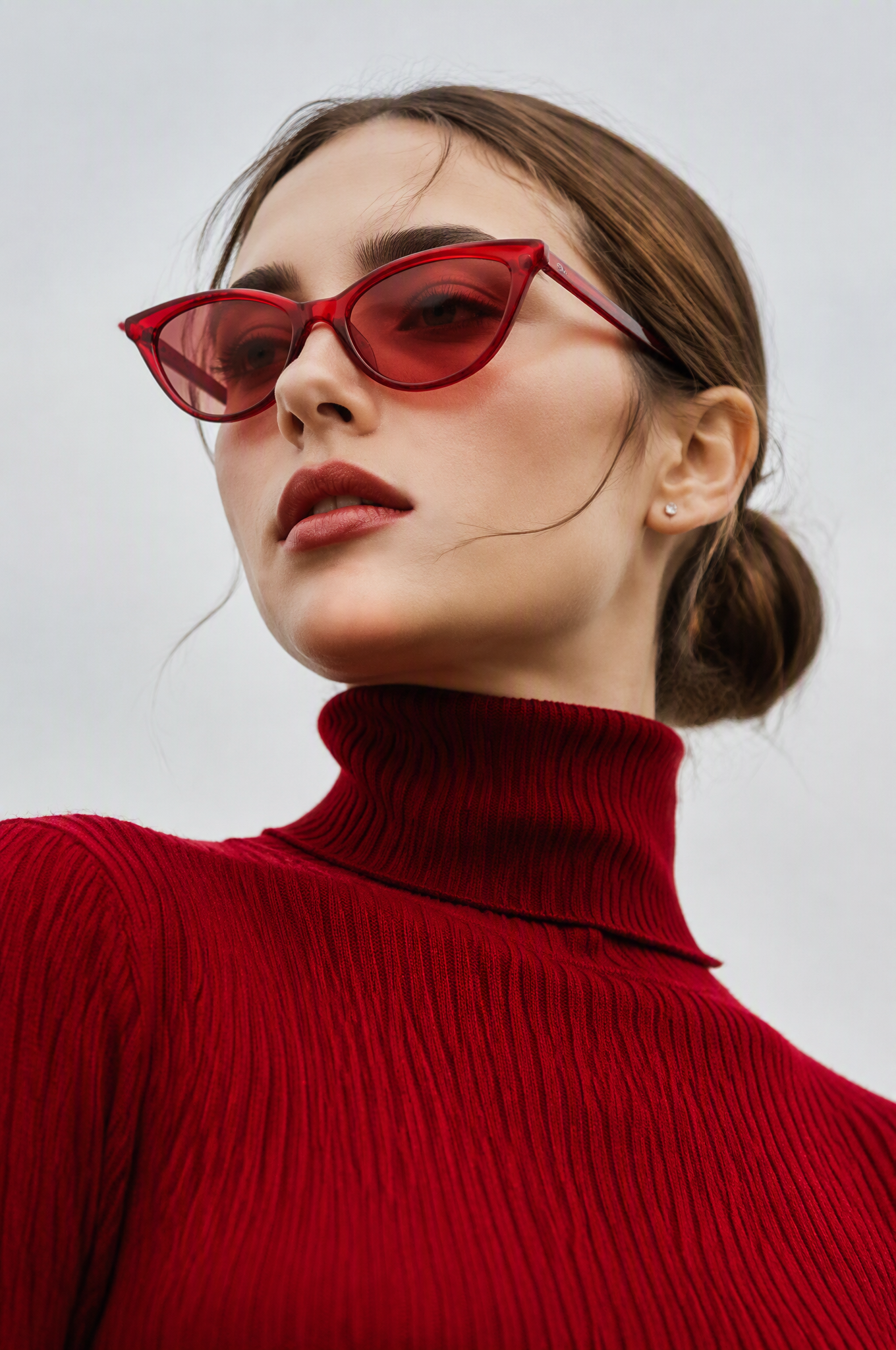 A low-angle editorial fashion portrait of a young woman w...