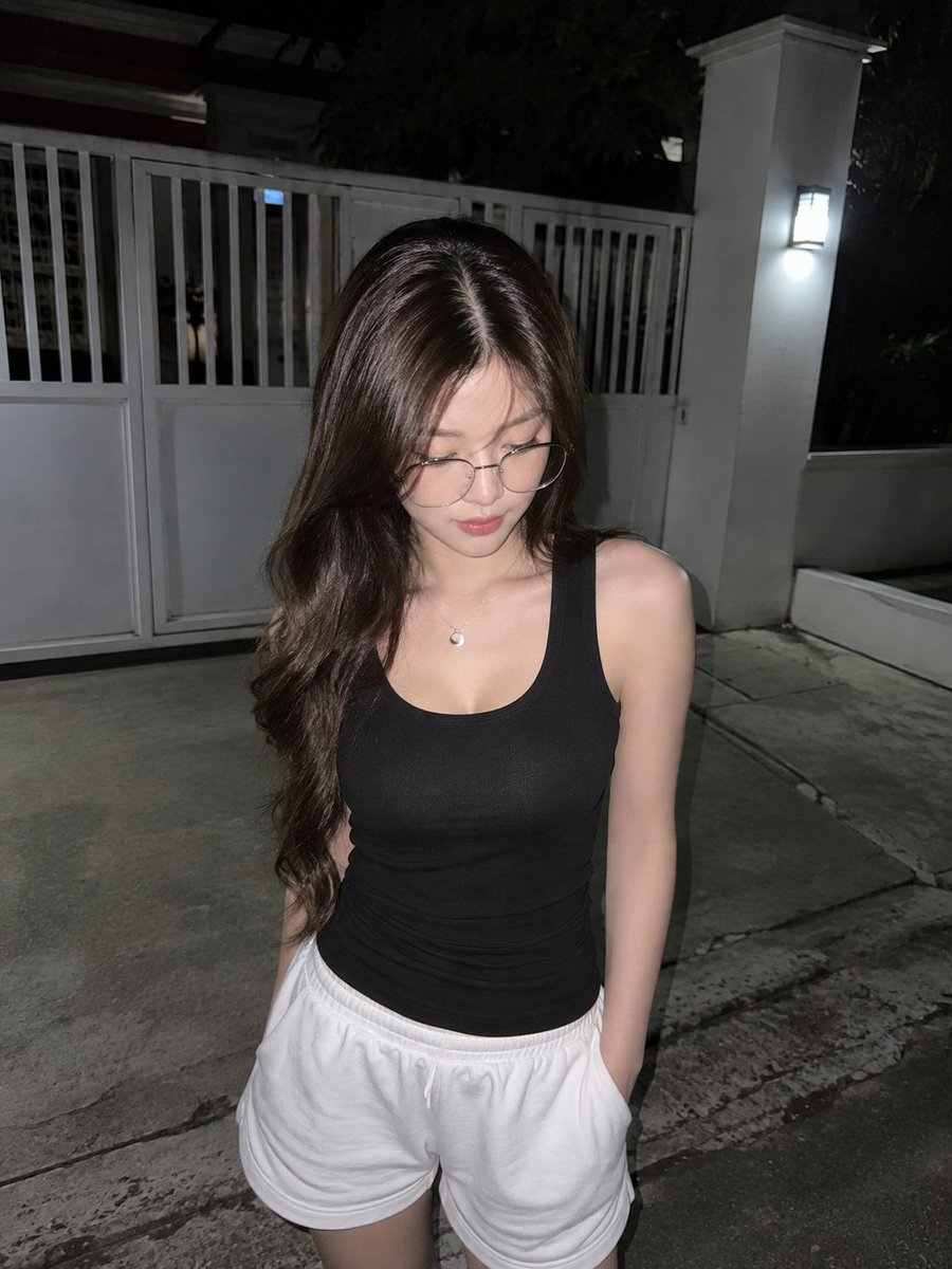A realistic direct-flash candid night photo of a young Ea...