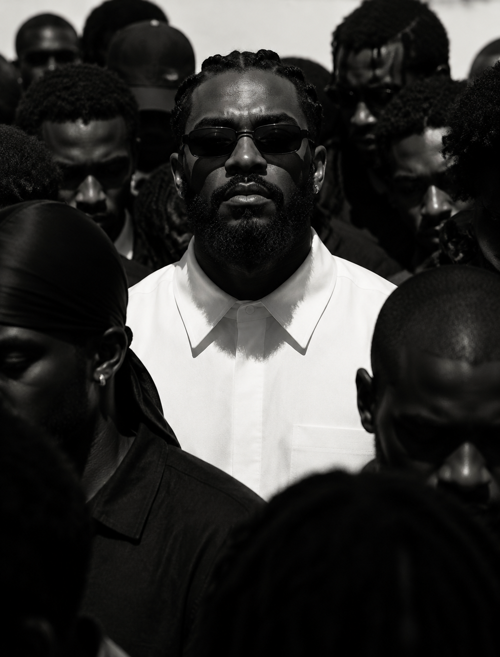 A composed Black man with braided hair, a full beard, and...
